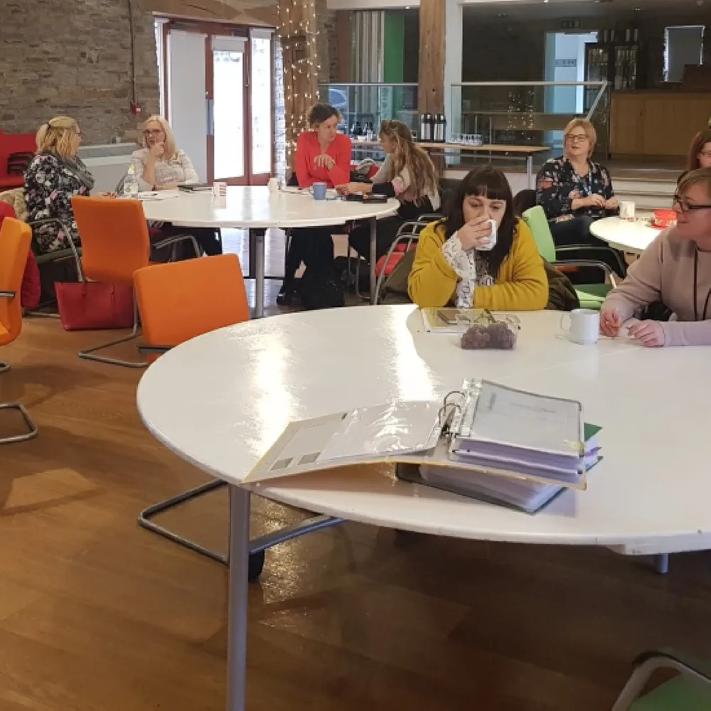 Photo of people sat around large round tables in our barn.