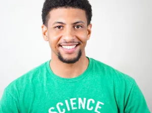 Photo of young man with beard smiling broadly, He's wearing a green shirt.