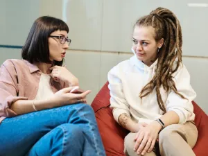 Photo of a young girl and older woman talking while seated