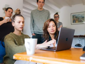 Photo of a group of six white young people - two seated at a laptop