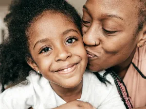 Image of a parent kissing their child on the cheek