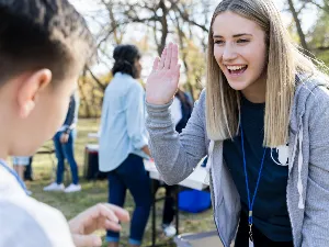 Image of a woman welcoming a young boy by a high five