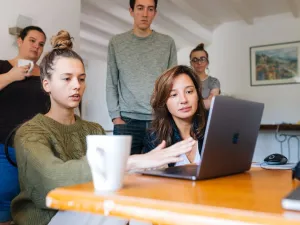 Photo of a group of six young people - two seated at a laptop