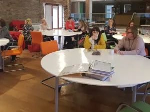 Photo of people sat around large round tables in our barn.