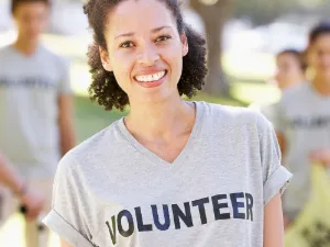 photo of a woman smiling and wearing a grey volunteer T shirt