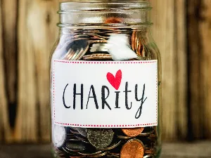 image of a glass jar filled with coins.  jar has a label saying charity