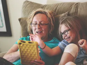 Photo of young girl and older woman using a tablet device. 