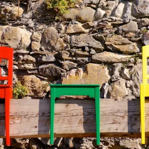 Colourful chairs against a stone wall