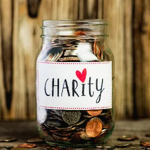 image of a glass jar filled with coins.  jar has a label saying charity