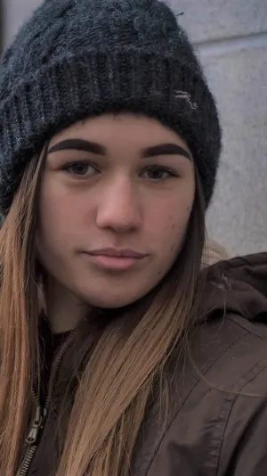 Photo of a young woman with long hair. She's wearing a grey woolly hat.