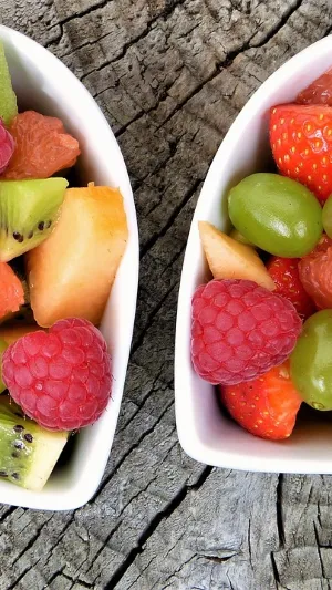 Two heart shaped bowls containing fruit salad.