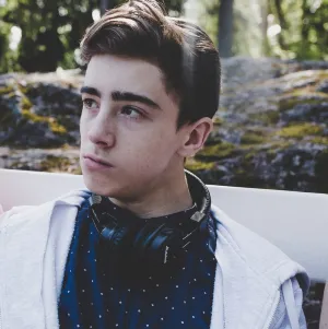 Photo of young man in a white jacket with headphones around his neck
