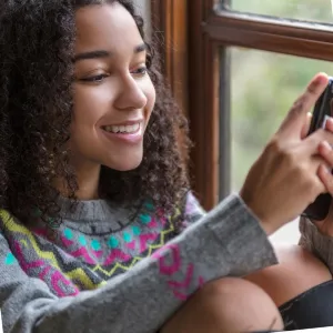 photo of a girl sitting in front of window on phone