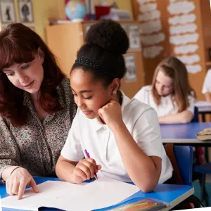 photo of classroom with teacher and girl sitting side by side 