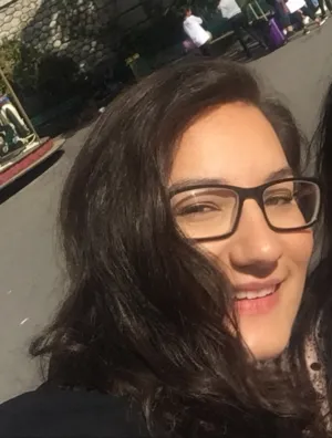 Photo of a young woman with dark hair. She is wearing glasses.